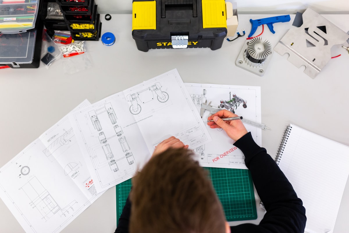 Schémas techniques étalés sur un établi, à côté d'une caisse à outils