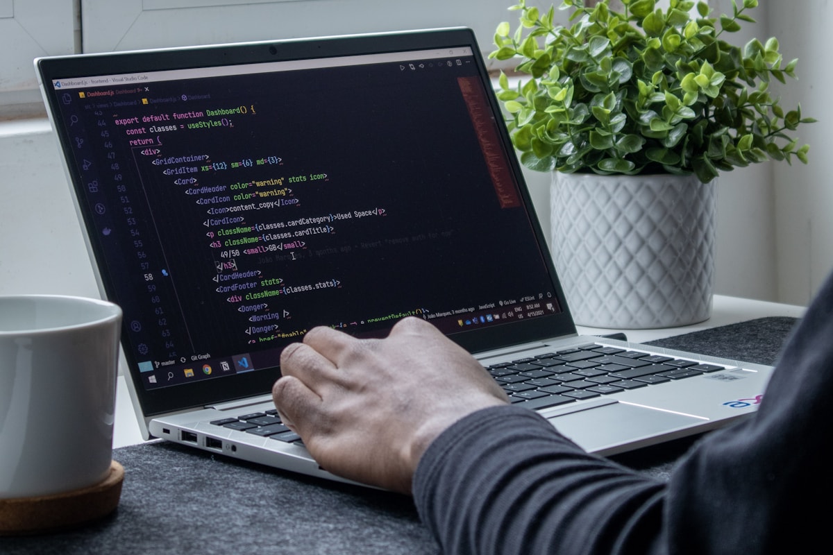 Personne en train de coder sur un portable, près d'une fenêtre